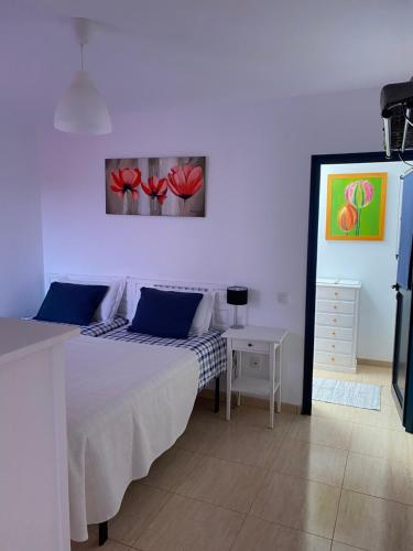 a bedroom with a bed and a table with red flowers on the wall at Casa Innès in Punta Mujeres