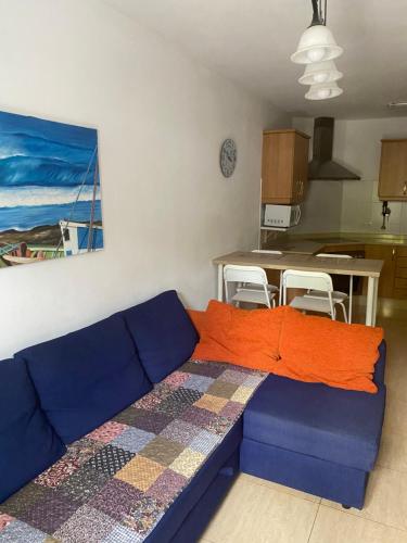 a living room with a blue couch with an orange blanket at Casa Innès in Punta Mujeres