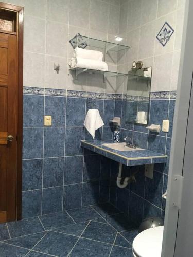 a blue tiled bathroom with a sink and a mirror at Casa Caribe in Bacalar