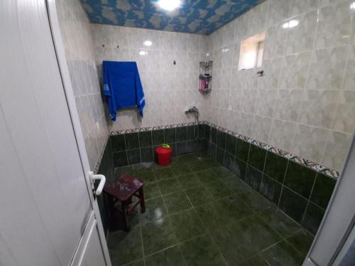 a bathroom with a shower with green tiles and a blue towel at Nabran Suite in Aşağıoba