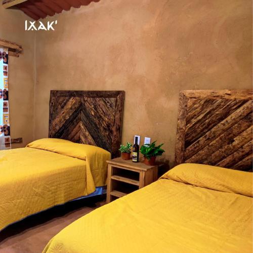 twee bedden in een kamer met gele lakens bij Ixak Cabañas 