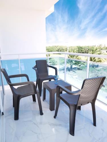 three chairs and a table on a balcony at Coconut Paradise Beach Hotel in Pajarito