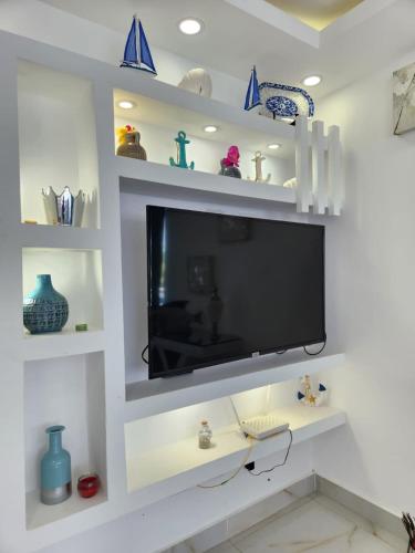 a tv in a living room with white shelves at Coconut Paradise Beach Hotel in Pajarito