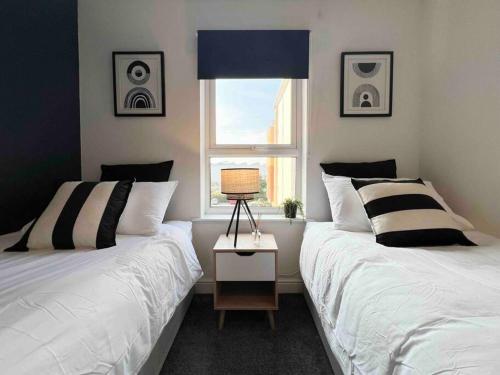 ハットフィールドにあるBeautiful Hatfield 2 Bedroom Apartment FREE Gated Parking - Modern Stylish - Business Park, Hertforshire University, St Albans, Welwyn Garden City, Luton Airport, Harry Potter Studio Tourのベッドルーム1室(ベッド2台付)、窓(スピーカー付)