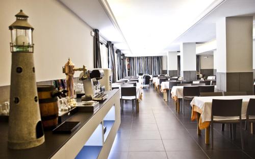 un comedor con mesas y sillas y un faro en Hotel Bon Repos, en Calella