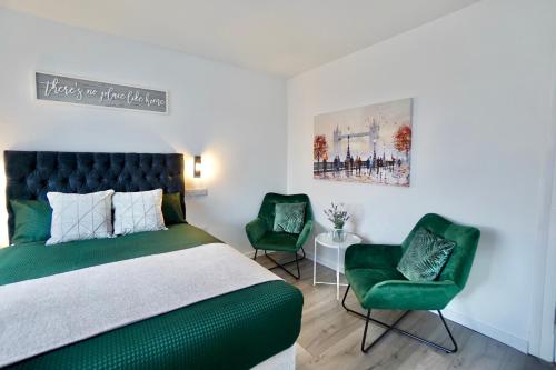 a bedroom with a green bed and two green chairs at Luxury Flats in Southsea Portsmouth in Portsmouth