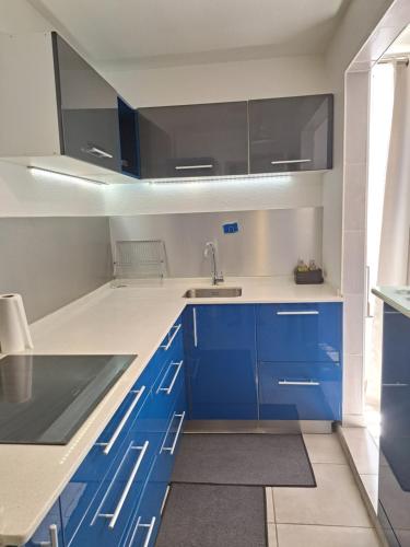 a kitchen with blue cabinets and a sink at Super appartement T3 proche de tout sans vis-à-vis in Fort-de-France