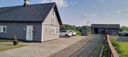 une petite maison avec des voitures garées dans un parking dans l'établissement Linderöd, à Linderöd