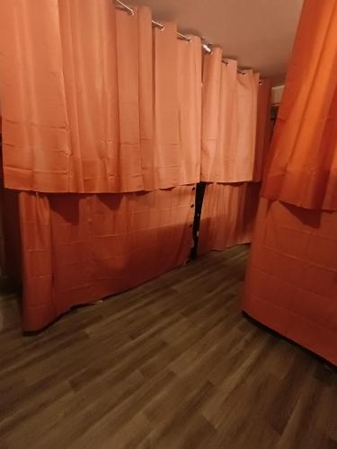 a room with orange curtains and a wooden floor at Backpackers Hostel in Dubai
