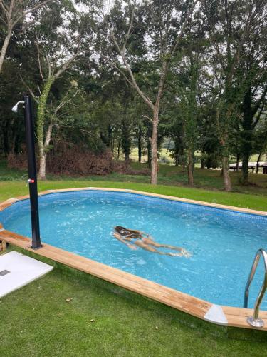 dos personas nadando en una piscina en el césped en Casa rural en Sigüeiro, Santiago de Compostela, en Sigüeiro