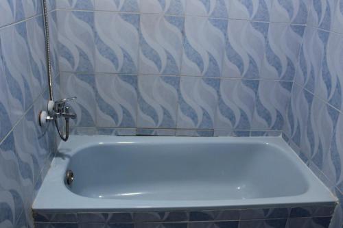 een badkamer met een bad en blauwe en witte tegels bij Anas Hostel in Wadi Musa