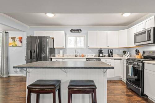 a kitchen with white cabinets and a large island with stools at The Bamboo House! Dog-Friendly Home n RVA Sleeps 8 in Richmond