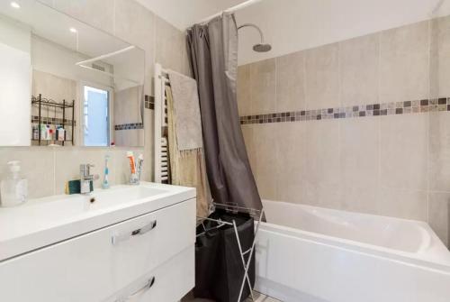 uma casa de banho com uma banheira branca, um lavatório e uma banheira tubermott em Appartement Paris Centre Vavin em Paris