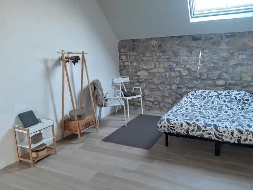 a bedroom with a bed and a stone wall at Guesthouse Le petit chapeau in Durbuy