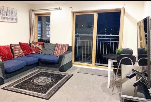 a living room with a blue couch and a balcony at 2 bedroom apartment city centre Birmingham in Birmingham