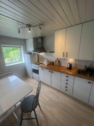 uma cozinha com armários brancos e uma mesa e uma mesa e uma cadeira em Cosy apartment with free parking em Bergen