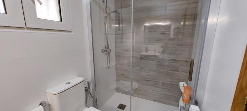 a bathroom with a toilet and a glass shower at Apartamento en urbanización lujo in Tavernes de Valldigna