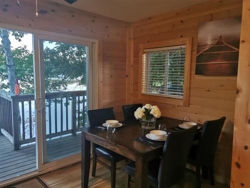 Muskoka Shores Cottages في ميناء كارلينج: غرفة طعام مع طاولة وكراسي على السطح