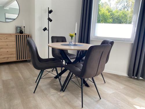 a dining room table with four chairs and a mirror at QT Apartments Detmold - Neu - Top Lage - Parkplatz in Detmold