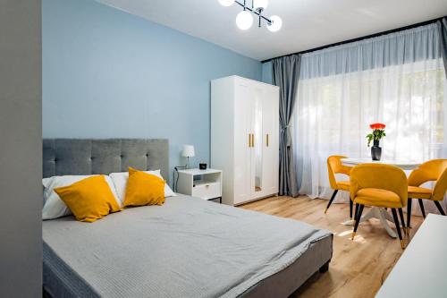 um quarto com uma cama com almofadas amarelas e uma mesa em Modern studio D-va N em Zalău
