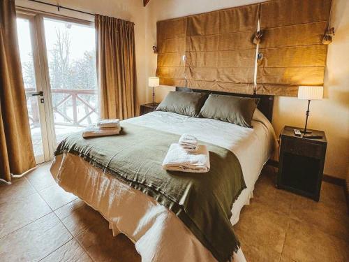 - une chambre avec un grand lit et une grande fenêtre dans l'établissement El Refugio de Montaña, à San Martín de los Andes