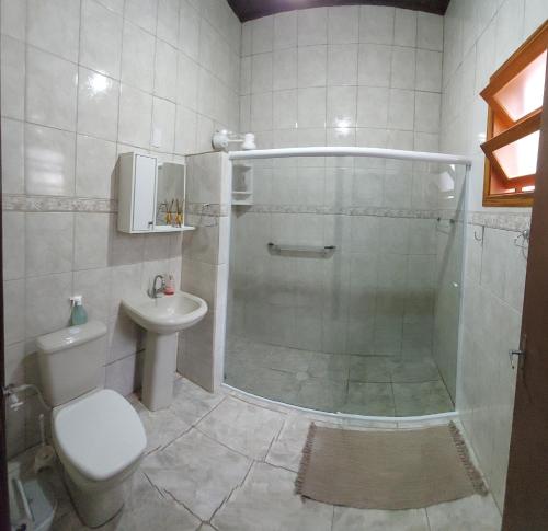 a bathroom with a shower and a toilet and a sink at Recanto Do Sossego Suítes Hospedagem Domiciliar na Praia in Boicucanga