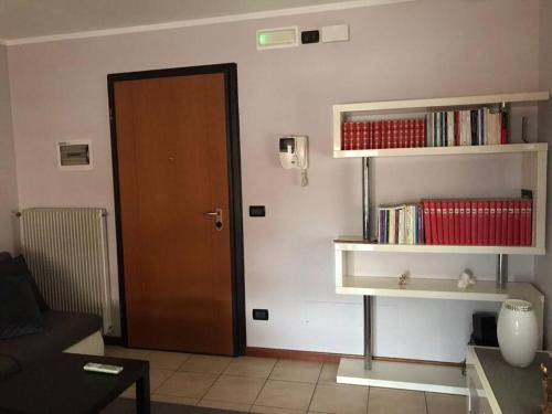 een woonkamer met een deur en planken met boeken bij Appartamento Elegante, Romantico e Riservato in Palazzolo dello Stella