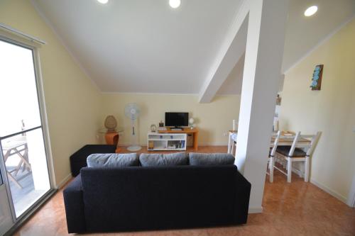 a living room with a couch and a tv at Casinha das Hortênsias in Horta