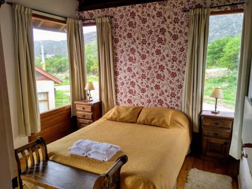 a bedroom with a bed and a table and windows at Cabañas Ayres del Lago 2 in Potrero de los Funes