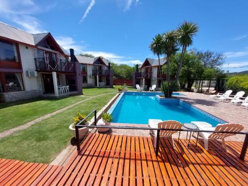 un patio trasero con piscina y una casa en Cabañas Ayres del Lago 2 en Potrero de los Funes