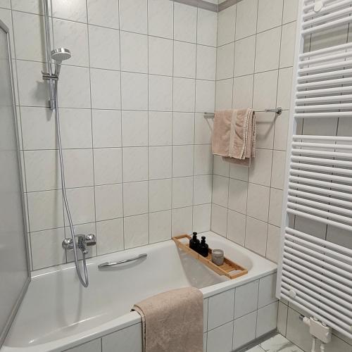 uma casa de banho branca com uma banheira e um chuveiro em Ferienwohnung an der Stadtmauer em Warburg