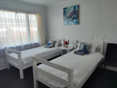 a room with two beds and a table and a window at Nesting In Hamilton East in Hamilton