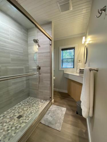 uma casa de banho com um chuveiro e uma porta de vidro em Canary Lake Cottage w/Hot Tub at Sam's Pizza em Hot Springs