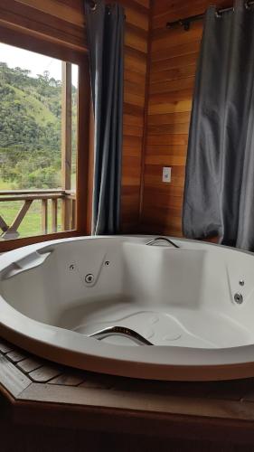 a large white bath tub in a room with a window at Chalé Vista Das Araucárias in Urubici