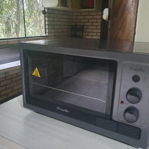 un horno de microondas sentado en un mostrador con una señal de advertencia en Sitio do Sol quarto wc compartilhado en Guabiruba