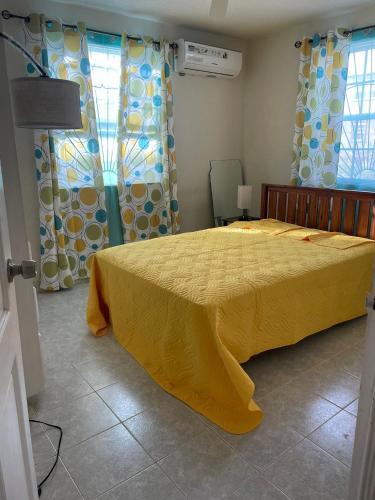 a bedroom with a bed with a yellow bedspread at Eastside Living "The Sunflower" in Saint Philip
