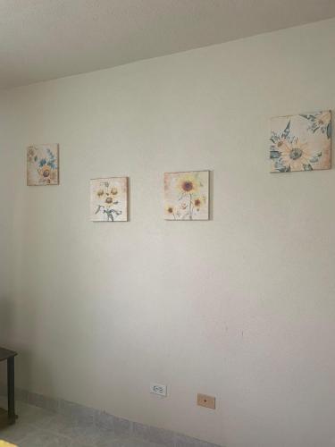 a white wall with four pictures of flowers on it at Eastside Living "The Sunflower" in Saint Philip