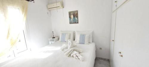a white bedroom with a bed with white sheets at By the sea in Andros