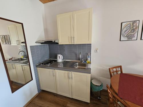 una pequeña cocina con armarios blancos y fregadero en Penzion pod Krivanom, en Liptovský Hrádok
