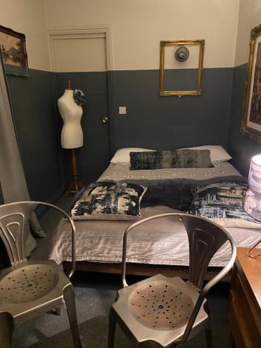 een slaapkamer met 2 bedden, 2 stoelen en een spiegel bij PAVILION ROOMS AT NO. 26 in Londen
