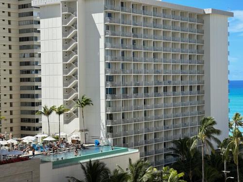 a large building with a swimming pool and a resort at WELLCOME TO LOVELY CONDO 2 BEDS 2 BATHS FREE PARKING IN WAIKIKI BEACH in Honolulu