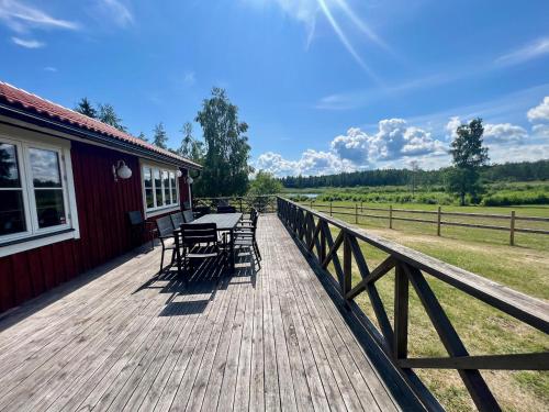 une terrasse en bois avec des tables et des chaises sur une maison dans l'établissement Idylliskt hus med sjöutsikt., à Östhammar