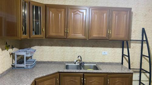 a kitchen with wooden cabinets and a sink at Petra Everest Hostel in ‘Ayn Amūn