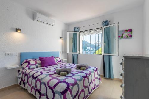 a bedroom with a bed with a purple and white comforter at Cap d´Or house in Moraira