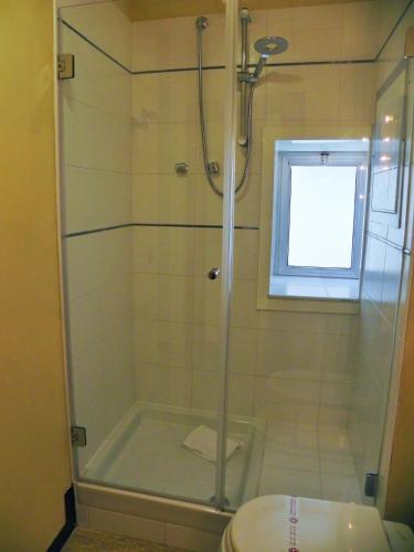 a bathroom with a shower with a toilet and a window at Torreata Hotel & Residence in Palermo