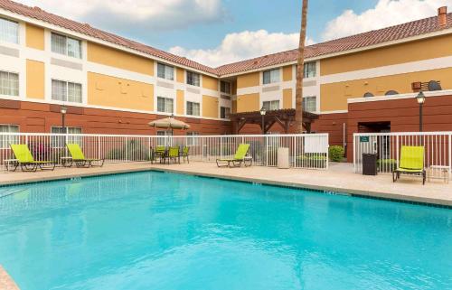 a swimming pool in front of a hotel with chairs and a building at Extended Stay America Suites - Phoenix - Scottsdale in Scottsdale