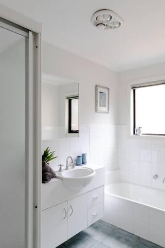 a white bathroom with a sink and a bath tub at Tyrone Sands Rye in Rye