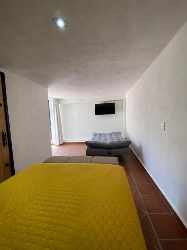 a bedroom with a yellow bed and a flat screen tv at Casa Laberinto in San Miguel de Allende