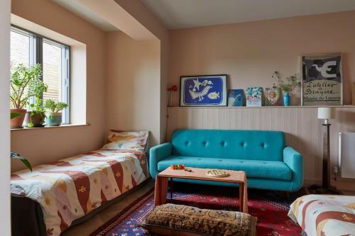 salon z niebieską kanapą i 2 łóżkami w obiekcie Nuthatch Retreat - Modern rustic ecohome with views w mieście Blakeney
