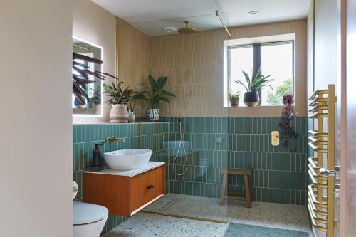 łazienka z umywalką, toaletą i zielonymi kafelkami w obiekcie Nuthatch Retreat - Modern rustic ecohome with views w mieście Blakeney
